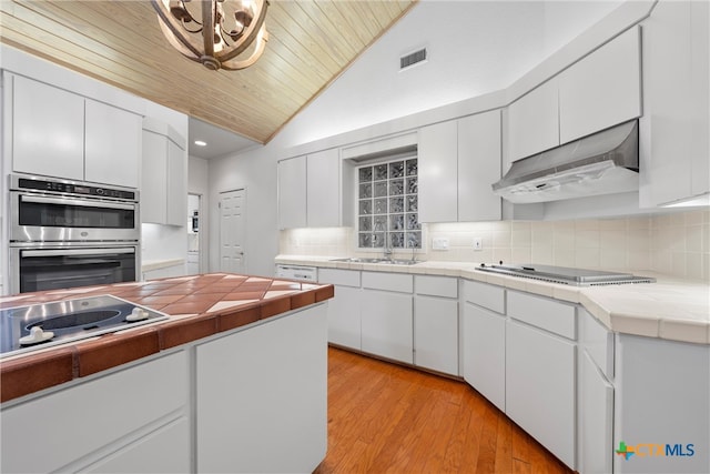 kitchen featuring tile counters, light hardwood / wood-style floors, white cabinets, and tasteful backsplash