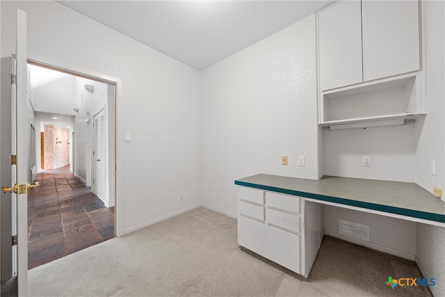 unfurnished office with built in desk and light colored carpet