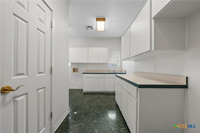 kitchen featuring white cabinetry, sink, and a textured ceiling