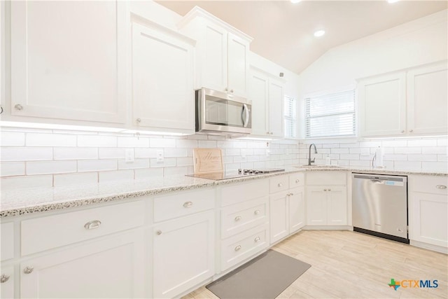 2306 Wooster St, Nolanville, TX 76559 - kitchen with white cabinets, a sink, appliances with stainless steel finishes, vaulted ceiling, and backsplash