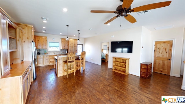 kitchen featuring a center island, hanging light fixtures, a kitchen breakfast bar, dark hardwood / wood-style floors, and stainless steel fridge