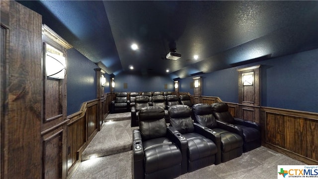 home theater room featuring decorative columns, wooden walls, a textured ceiling, and carpet