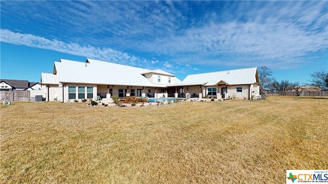 back of house with central AC unit and a yard