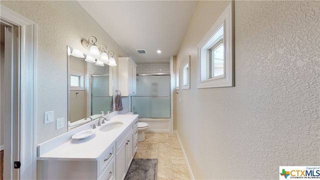 full bathroom featuring toilet, vanity, and shower / bath combination with glass door