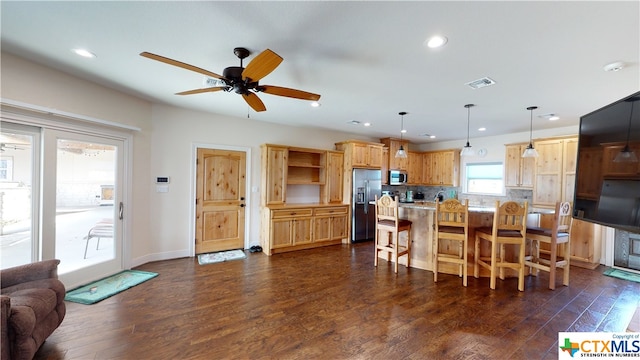 kitchen with dark hardwood / wood-style flooring, pendant lighting, a kitchen bar, and stainless steel appliances