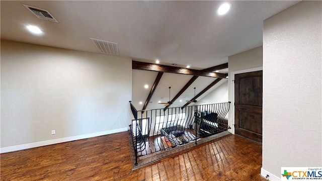 staircase featuring hardwood / wood-style floors, ceiling fan, and lofted ceiling with beams