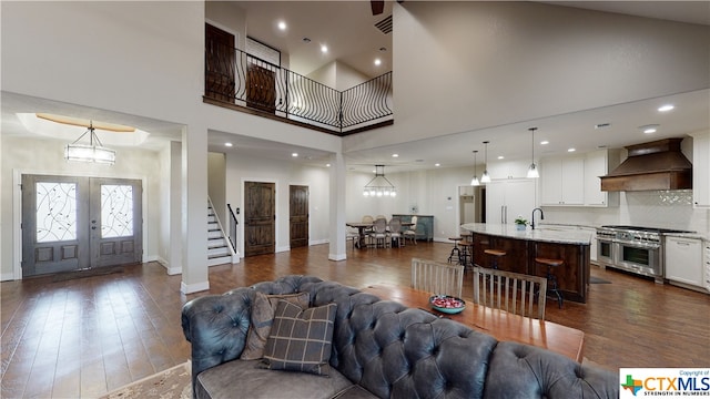 living room featuring a towering ceiling, a notable chandelier, french doors, and dark hardwood / wood-style flooring