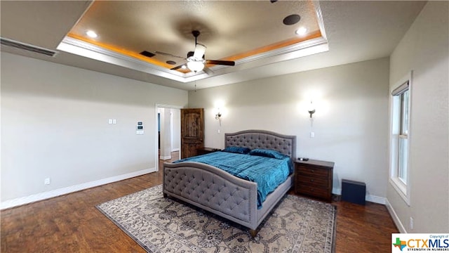 bedroom featuring multiple windows, ceiling fan, dark hardwood / wood-style floors, and a tray ceiling