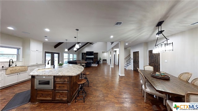 kitchen featuring dark hardwood / wood-style flooring, a wealth of natural light, sink, and an island with sink