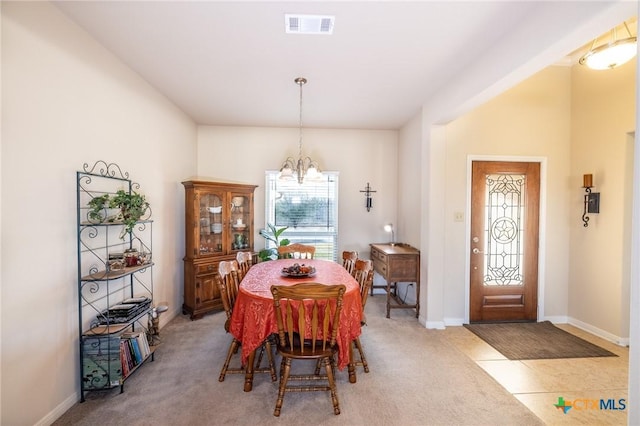 dining space featuring light colored carpet and a notable chandelier