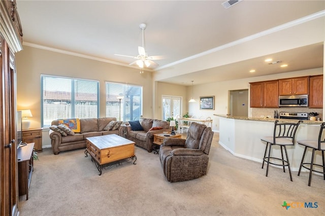 living room featuring light carpet, ceiling fan, and crown molding