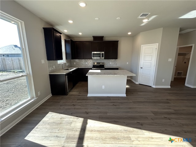 kitchen featuring stainless steel appliances, a center island, dark hardwood / wood-style floors, and decorative backsplash