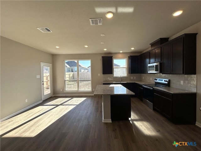 kitchen featuring sink, light stone counters, dark hardwood / wood-style floors, a kitchen island, and stainless steel appliances