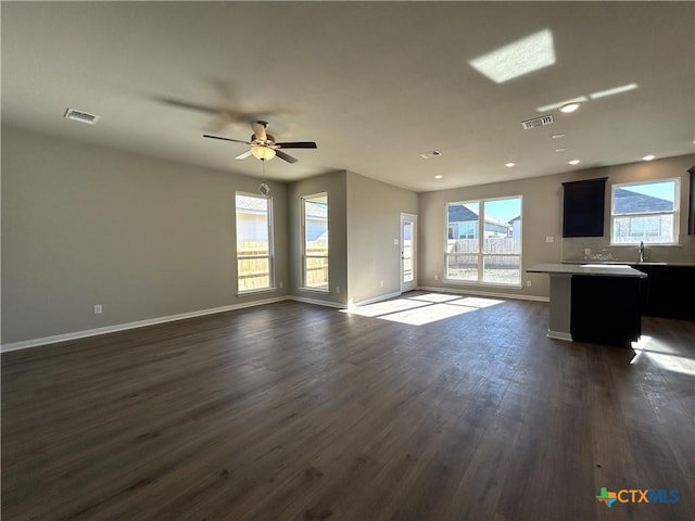 unfurnished living room with ceiling fan, a healthy amount of sunlight, dark hardwood / wood-style flooring, and sink