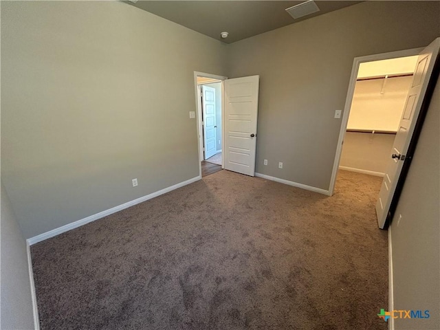 unfurnished bedroom with a closet, carpet flooring, and a spacious closet