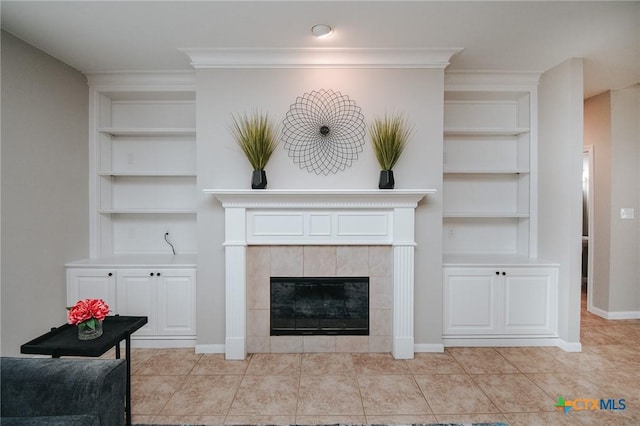 living room with built in features, a tile fireplace, crown molding, and baseboards