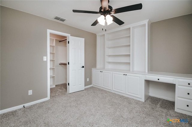 unfurnished bedroom with light carpet, baseboards, visible vents, built in study area, and a spacious closet