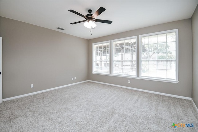 carpeted empty room with ceiling fan, visible vents, and baseboards