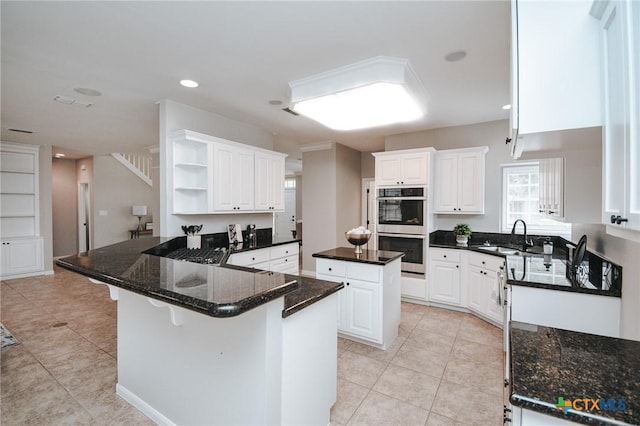 kitchen with light tile patterned floors, white cabinets, double oven, open shelves, and a sink