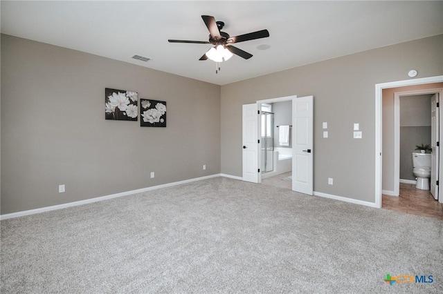 unfurnished bedroom with light colored carpet, visible vents, ensuite bathroom, a ceiling fan, and baseboards