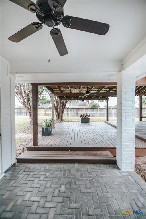 exterior space with a ceiling fan, decorative driveway, fence, and a wooden deck