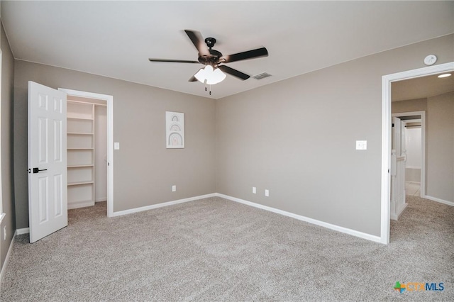 unfurnished bedroom with ceiling fan, carpet floors, visible vents, baseboards, and a spacious closet