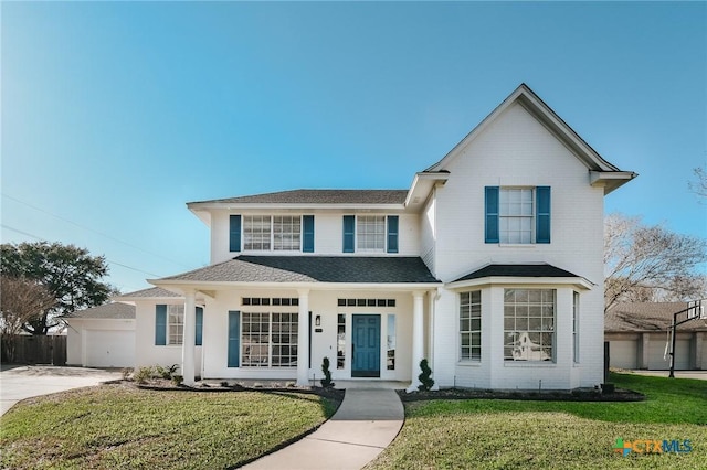 traditional home with a shingled roof, fence, a front lawn, and concrete driveway