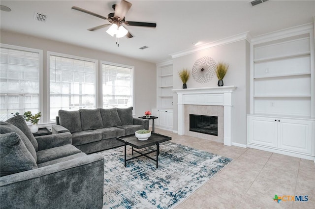 living room with light tile patterned floors, visible vents, built in features, and a tiled fireplace