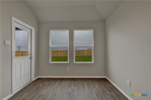 spare room with hardwood / wood-style flooring and vaulted ceiling