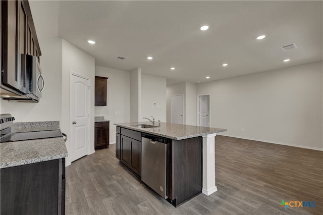 kitchen with light hardwood / wood-style flooring, a kitchen island with sink, light stone counters, and stainless steel appliances