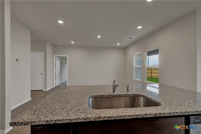 kitchen featuring dark hardwood / wood-style flooring, light stone countertops, sink, and dishwashing machine