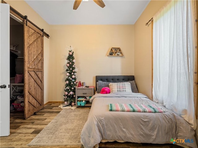 12093 Sulphur Springs Rd, Adkins, TX 78101 - bedroom featuring wood finished floors, a barn door, a ceiling fan, and baseboards