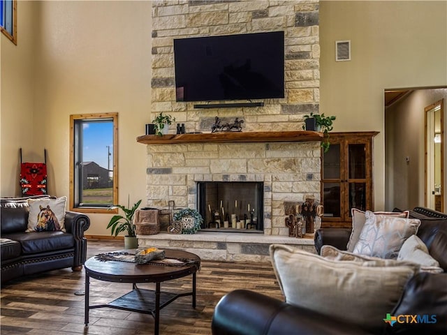 12093 Sulphur Springs Rd, Adkins, TX 78101 - living area with wood finished floors, a stone fireplace, a high ceiling, and baseboards