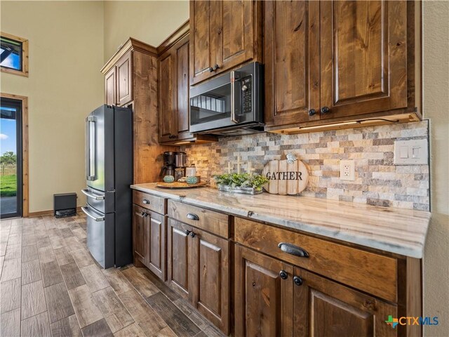 12093 Sulphur Springs Rd, Adkins, TX 78101 - kitchen featuring appliances with stainless steel finishes, backsplash, wood finished floors, light stone counters, and a towering ceiling
