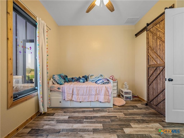 12093 Sulphur Springs Rd, Adkins, TX 78101 - bedroom with a barn door, wood finished floors, and baseboards