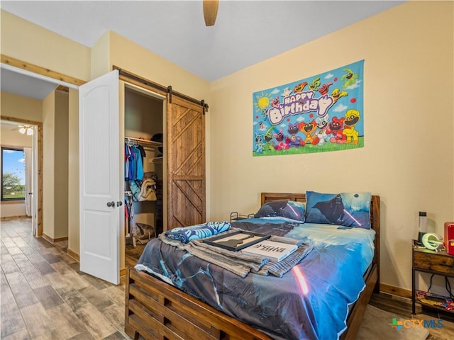 12093 Sulphur Springs Rd, Adkins, TX 78101 - bedroom featuring a barn door, wood finished floors, baseboards, and a closet