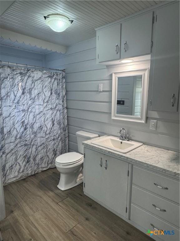 bathroom with curtained shower, toilet, vanity, and hardwood / wood-style flooring