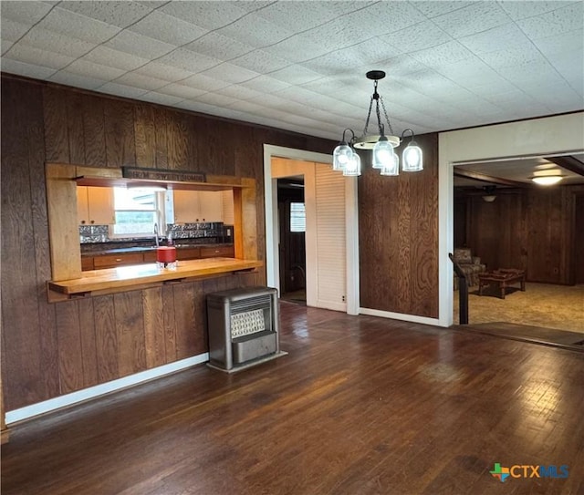 kitchen with butcher block counters, dark hardwood / wood-style flooring, kitchen peninsula, and wooden walls