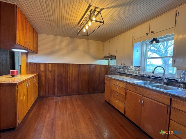 kitchen with dark hardwood / wood-style floors, wood walls, wood ceiling, and sink