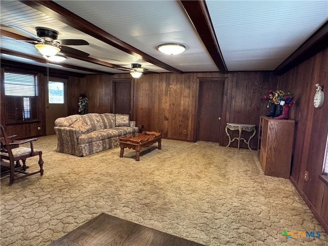 living room featuring ceiling fan, wood walls, light colored carpet, and beam ceiling