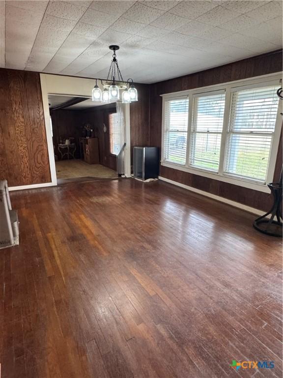 unfurnished dining area featuring wood walls and dark wood-type flooring