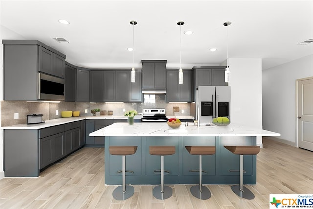 kitchen with appliances with stainless steel finishes, gray cabinetry, and an island with sink