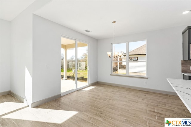 unfurnished dining area featuring a chandelier and light wood-type flooring