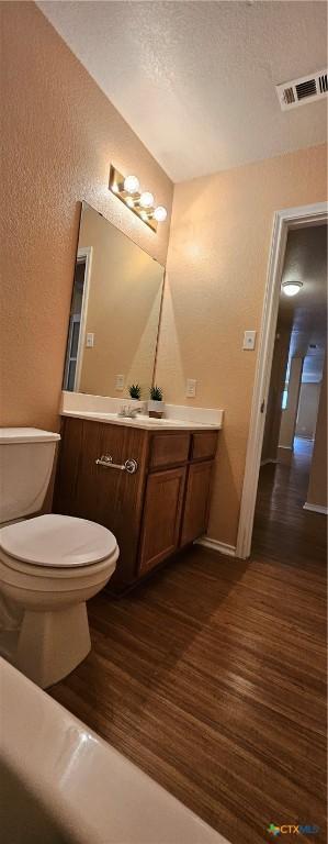 bathroom with hardwood / wood-style flooring, vanity, toilet, and a textured ceiling