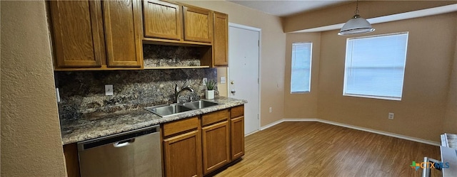 kitchen with sink, decorative light fixtures, light hardwood / wood-style flooring, stainless steel dishwasher, and decorative backsplash