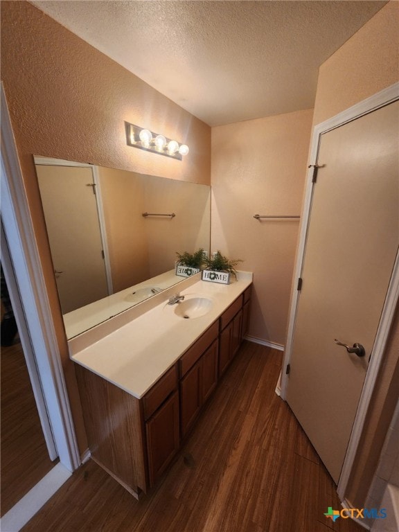 bathroom with a textured ceiling, vanity, and wood-type flooring