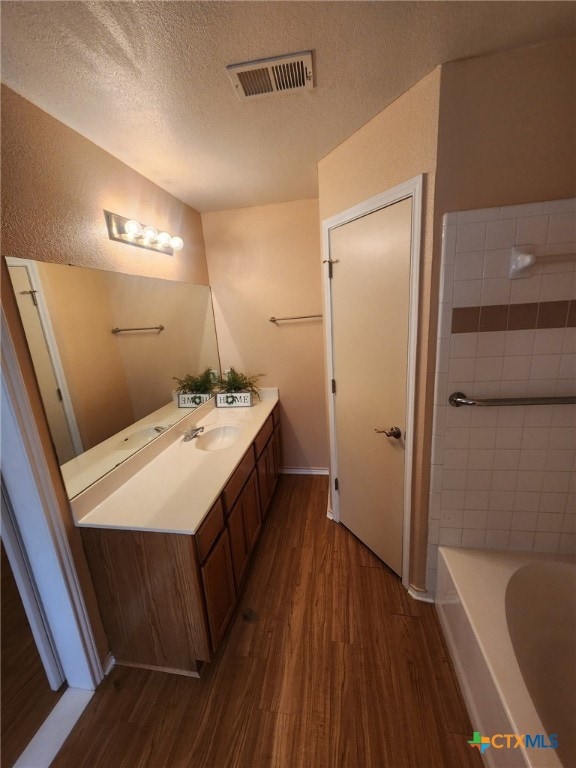 bathroom featuring a textured ceiling, vanity, a bathtub, and wood-type flooring