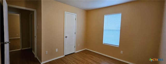 unfurnished bedroom with multiple windows and wood-type flooring