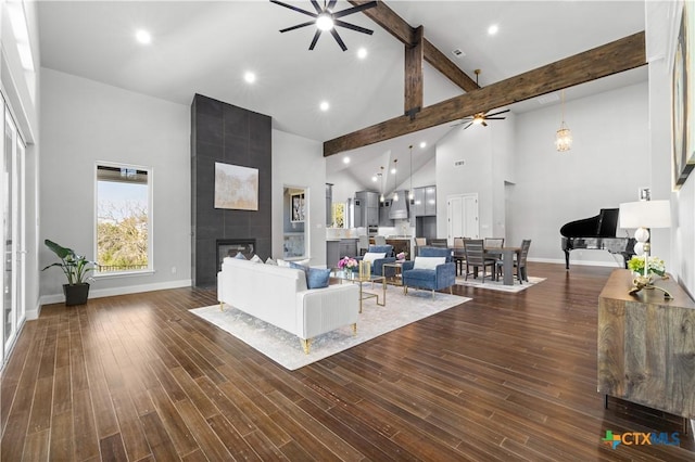 living room with dark wood finished floors, a fireplace, high vaulted ceiling, beamed ceiling, and baseboards