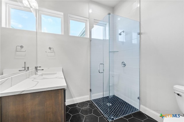 full bathroom featuring toilet, a sink, baseboards, a shower stall, and double vanity